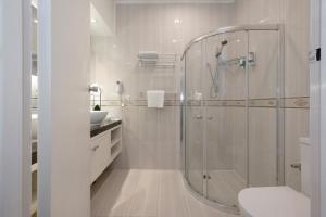 a white bathroom with a shower and a toilet at Adelaide Granada Motor Inn in Adelaide