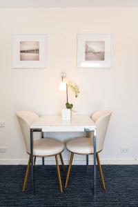a dining room table and chairs with a white wall at Adelaide Granada Motor Inn in Adelaide