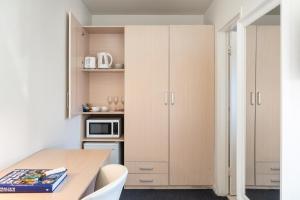 una pequeña cocina con mesa de madera y armarios blancos en Adelaide Granada Motor Inn, en Adelaida