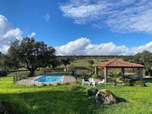a swimming pool with two chairs and a gazebo at LIDENEX in Guijo de Granadilla