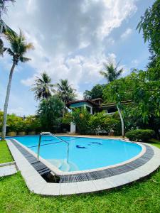 a swimming pool in front of a house with palm trees at Leijay Garden Retreat in Galle
