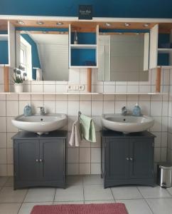 a bathroom with two sinks and a mirror at De Dackluuk in Wittmund