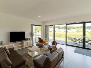 een woonkamer met een bank en een flatscreen-tv bij 16p group accommodation in 2 villas on the water in Zeewolde