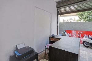 een kamer met een bureau, een tafel en een raam bij OYO Flagship 84221 Marvel Inn in Nagpur