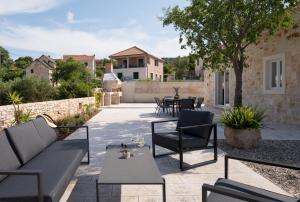 un patio con divano, sedie e tavolo di NEW! Stone Villa Olim Civitas with 3 bedrooms, private pool, and sea views a Škrip
