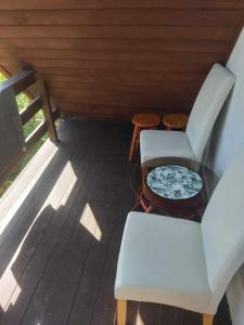 two white chairs and a table on a porch at Uroczy domek letniskowy z kominkiem 100m2 in Bogaczewo