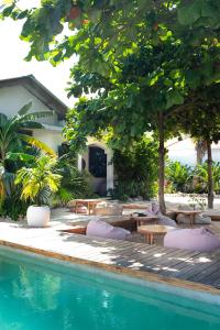 a pool with chairs and tables next to a house at Dar Mar Hostel & Coworking in Paje +111 photos