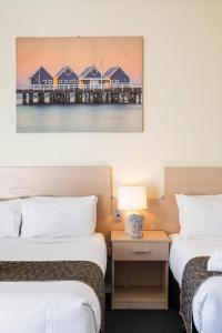 two beds in a hotel room with a picture of a pier at Adelaide Granada Motor Inn in Adelaide