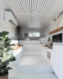 a living room with white furniture and a plant at Leobus-לאו באס in Menaẖemya