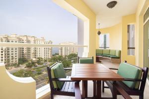 een balkon met een houten tafel en stoelen en een groot raam bij Royal Club By RVHR, Palm Jumeirah in Dubai