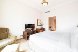 a white bedroom with a bed and a couch at Royal Club By RVHR, Palm Jumeirah in Dubai