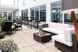 a patio with white furniture and tables and chairs at IntercityHotel Wien in Vienna