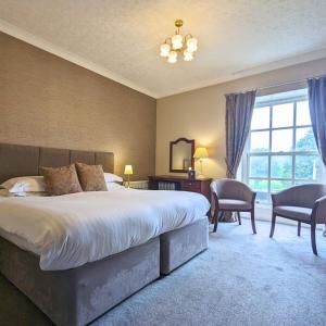 ein Schlafzimmer mit einem großen Bett, einem Tisch und Stühlen in der Unterkunft Shaw Hill Hotel Golf And Country Club in Chorley