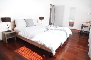 una camera da letto con un letto con lenzuola bianche e un pavimento in legno di Nest - Bundesstrasse 6 a Zugo