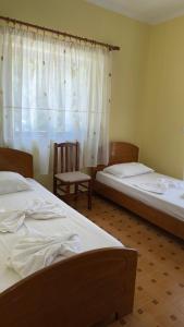 a bedroom with two beds and a chair and a window at Hotel Nemercka in Përmet