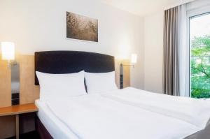 a large bed in a hotel room with a window at IntercityHotel Wien in Vienna