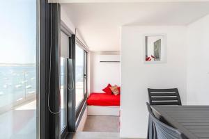 Cette chambre comprend un lit rouge et une fenêtre. dans l'établissement SkyView Penthouse, Mell_4, à Mellieħa