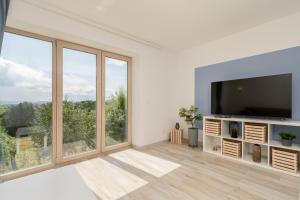 a living room with a flat screen tv and large windows at Mieszkanie pod Lipą 