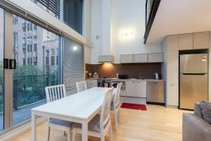 uma cozinha e sala de jantar com uma mesa branca e cadeiras em New York Lofted CBD Retreat with Pool and Parking em Melbourne