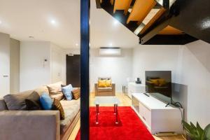 uma sala de estar com um sofá e um tapete vermelho em New York Lofted CBD Retreat with Pool and Parking em Melbourne