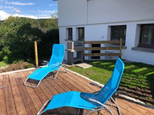 twee blauwe stoelen op een houten terras bij Appartement du parc in Xonrupt-Longemer