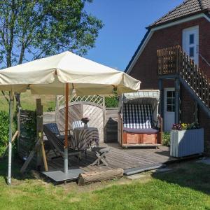 eine Terrasse mit einem Sonnenschirm und 2 Stühlen auf einer Terrasse in der Unterkunft Nordsee & Wald in Husum