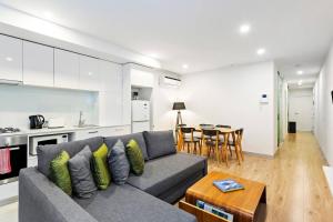 ein Wohnzimmer mit einem grauen Sofa und einem Tisch in der Unterkunft Carlton Delight - Patio Abode near Queen Vic Market in Melbourne
