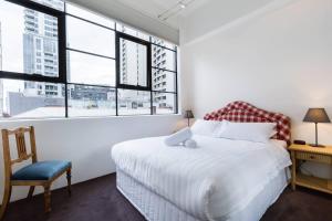 Schlafzimmer mit einem Bett, einem Stuhl und Fenstern in der Unterkunft New York Style Loft on Flinders Lane with Parking in Melbourne