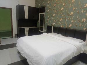 een slaapkamer met een wit bed en een groene muur bij OYO Hotel Rajdeep in Agra