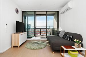 a living room with a couch and a large window at Resort-style Docklands Riverview Stay with Parking in Melbourne