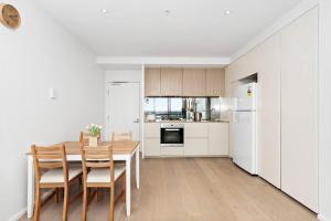 a kitchen with a table and chairs and a refrigerator at Resort-style Docklands Riverview Stay with Parking in Melbourne