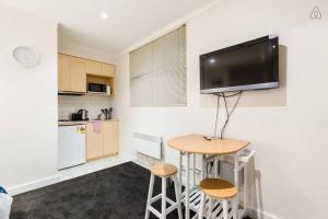 uma cozinha com uma mesa e uma televisão na parede em 'Ann Student Studio' Queen Pad on Lygon Street em Melbourne