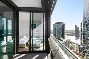 a room with a bed on the balcony of a building at Resort-style Docklands Riverview Stay with Parking in Melbourne