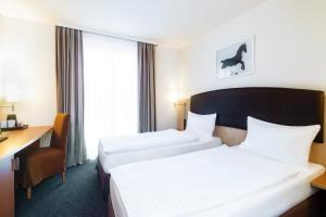 a hotel room with two beds and a desk at IntercityHotel Wien in Vienna