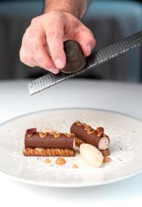 una persona sosteniendo una cuchara sobre un plato de comida en InterContinental Bordeaux Le Grand Hotel, an IHG Hotel, en Burdeos