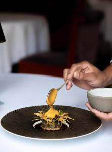 una persona usando una cuchara en un plato con un tazón en InterContinental Bordeaux Le Grand Hotel, an IHG Hotel en Burdeos
