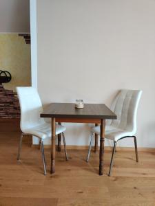 una mesa de madera con 2 sillas blancas alrededor en Festl Apartments - Nähe Messe München, Therme Erding, en Forstern