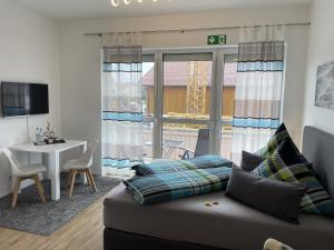 a living room with a couch and a table and a window at Festl Apartments - Nähe Messe München, Therme Erding in Forstern