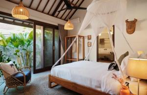 Un dormitorio con una cama con dosel y una silla. en Villa Alba, en Kuta Lombok 40 fotos más