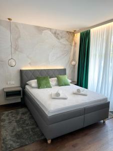 a bedroom with a large bed with two green pillows at Rooms Lidija in Zagreb