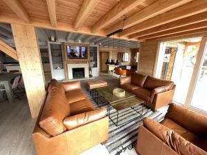 a living room with leather furniture and a fireplace at Odalys Chalet Le Chabichou in Les Deux Alpes