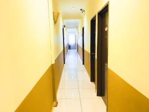 um corredor com paredes amarelas e piso em azulejo em Sun Inns Hotel Equine, Seri Kembangan em Seri Kembangan