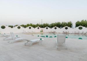 einen Pool mit Stühlen und einem Tisch neben einer Wand in der Unterkunft Casal Duca in Taranto