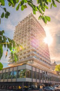 un edificio alto con el sol brillando en él en Hotel Kyiv en Kiev