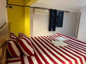 um quarto com uma cama com riscas vermelhas e brancas em Por Chey em Battambang