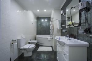a white bathroom with a toilet and a sink at Hotel Kyiv in Kyiv