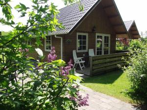 Cabaña con porche y silla en el porche en Vakantiehuisjes Landgoed Sonneborghe en Kollumerzwaag
