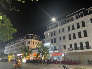 un grupo de personas sentadas fuera de los edificios por la noche en Basic Guest House Hải Phòng, en Hai Phong