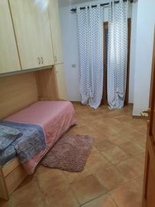 a room with a bed and curtains and a tile floor at Casa vacanza 70 mq in Valledoria