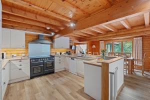 a kitchen with white cabinets and a stove at Finest Retreats - The Logs in Fort William